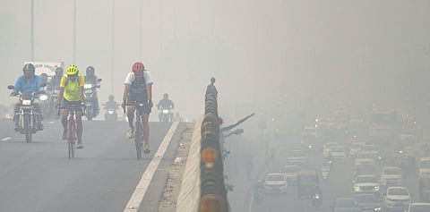 People ride their bicycles on the Gurugram-Delhi Expressway amid low visibility due to smog, in Gurugram, on November 3, 2022. (Photo | PTI)