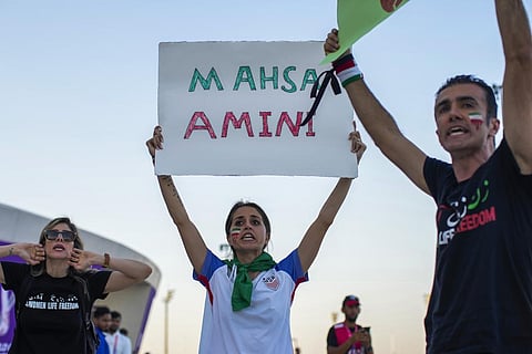 A woman holds up a sign reading Mahsa Amini, a woman who died while in police custody in Iran, during a protest after the World Cup match between Wales and Iran.  (Photo | AP)