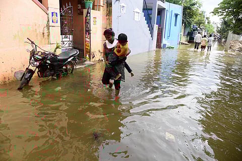People walk on a waterlogged street at JJ Nagar, Manali, in Chennai. (Photo | R Satish Babu, EPS)