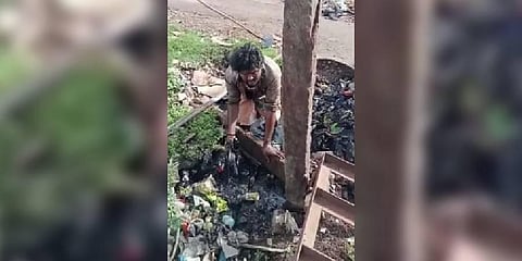 Sanitary worker cleaning a clogged sewer with bare hands