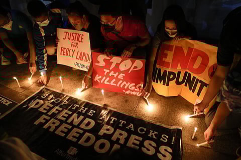 Activists light candle beside slogans as they condemn the killing of Filipino journalist Percival Mabasa during a rally in Quezon city, Philippines on Oct. 4, 2022. (Photo | AP)