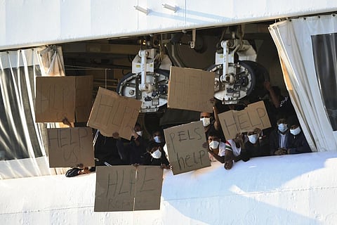 Migrants hold banners asking for help, from a deck of the Norway-flagged Geo Barents ship operated by Doctors Without Borders, in Catania's port, Sicily, Oct. 7, 2022. (File Photo | AP)