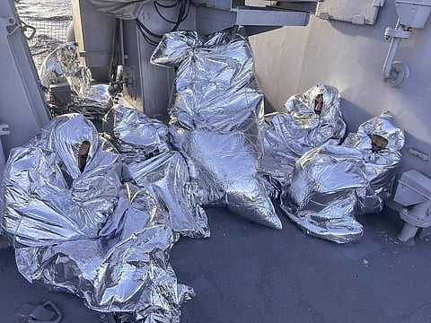 Some of the nine men who survived a shipwreck are covered with a thermal blankets as they sit aboard a Greek Coast guard vessel, in the Aegean Sea, Greece. (Photo | Greek Coast Guard via AP)