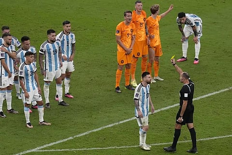 Referee Antonio Mateu shows a yellow card to Argentina's Lionel Messi during the World Cup quarterfinal soccer match against Netherlands at the Lusail Stadium in Lusail, Qatar, Dec. 10, 2022.