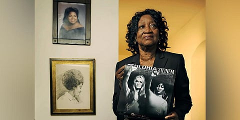 Dorothy Pitman Hughes is pictured in her home in 2013, with a poster using a 1970s image of herself and Gloria Steinem. (Photo | AP)