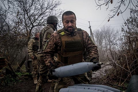 A Ukrainian artilleryman from the 24th brigade carries a 122mm shell for a 2S1 Gvozdika self-propelled howitzer at a position along the front line in Bakhmut, Donetsk region. (Photo | AFP)