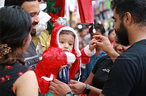 As families get into the Christmas spirit, a toddler is dressed up in a Santa Claus costume at Broadway in Kochi. 