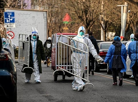Health workers wearing personal protective equipment carry barricades inside a residential community that just opened after a lockdown due to Covid-19 restrictions in Beijing. (Photo | AFP)