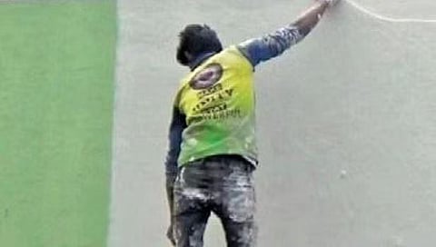 A labourer paints white colour over green at the entrance wall of Kalaburagi Railway Station on Tuesday. (EPS)