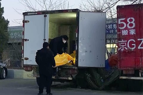 Workers load body bags into a truck at a funeral complex in Beijing on December 16, 2022.