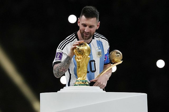 Argentina's Lionel Messi pats the trophy after winning the World Cup final  match against France at the Lusail Stadium in Qatar. 