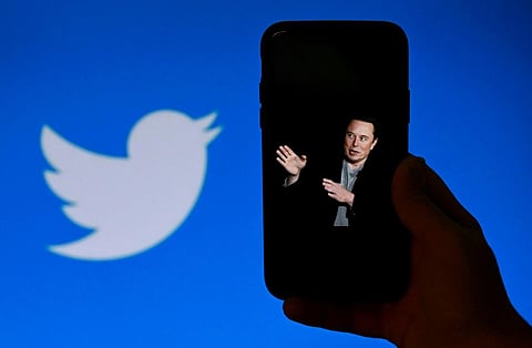 A phone screen displays a photo of Elon Musk with the Twitter logo shown in the background. (Photo | AFP)