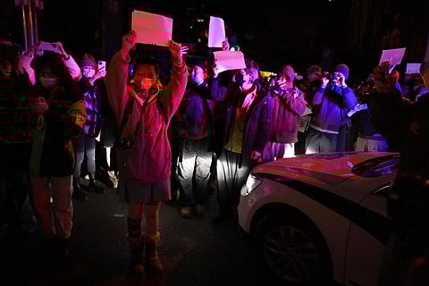 Protesters hold up blank papers and chant slogans as they march in protest in Beijing, Nov. 27, 2022.  (File photo | AP)