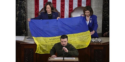 U.S. Vice President Kamala Harris and House Speaker Nancy Pelosi react as Ukrainian President Volodymyr Zelenskyy presents lawmakers with a Ukrainian flag autographed by front-line troops.(Photo | AP)