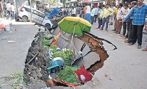 Passersby take a look at the vehicles and vegetables that fell into the collapsed road in Goshamahal area on Friday | Jwala