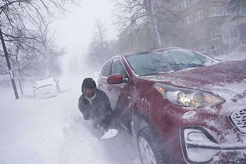 Gamaliel Vega tries to dig out his car on Lafayette Avenue after he got stuck in a snowdrift about a block from home while trying to help rescue his cousin. (Photo | AP)