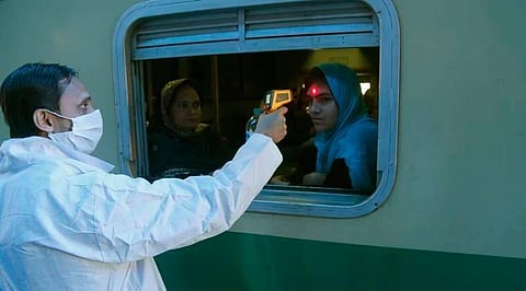 A Pakistani volunteer checks the body temperature of a passenger to help detect coronavirus, at a railway station in Lahore, Pakistan, March 18, 2020. (File Photo | AP)