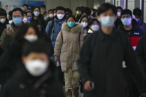 Masked commuters walk through a walkway in between two subway stations as they head to work during the morning rush hour in Beijing. (Photo | AP)