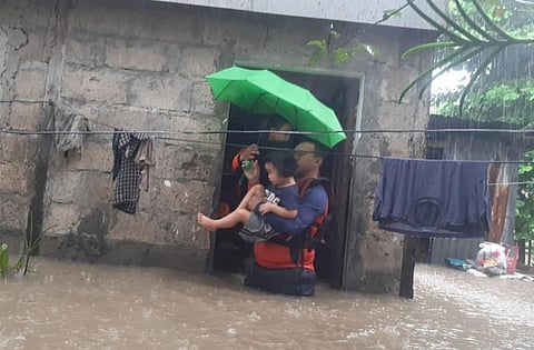 Rescuers evacuate a child from a flooded area in Ozamiz City, Misamis Occidental, Philippines on Sunday. (Photo | AFP)