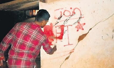 A policeman masks the graffiti from a wall in Shiralakoppa, Shikaripura taluk