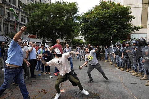 Protesters throw bottles glasses at the Lebanese Central Bank building, background, where the anti-government demonstrators rally against the Lebanese Central Bank. (Photo | AP)