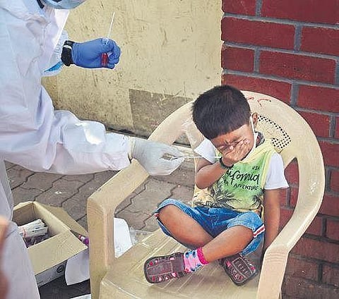 A health worker tries to collect swab sample of a child in Bengaluru on Monday | shriram bn