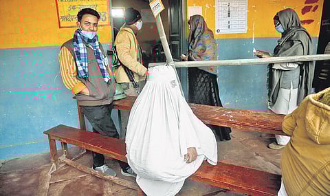 People waiting to press the button; Voters get their temperature checked as a precautionary Covid-19 measure at the entrance of a polling station; a citizen gets her finger marked with indelible ink a