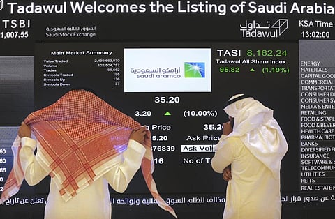 Saudi stock market officials watch the stock market screen displaying Saudi Arabia's state-owned oil company Aramco after the debut of Aramco's initial public offering. (Photo | AP)