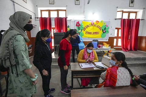 Students wait to receive their dose of COVID-19 vaccine at a government school in Jammu. (Photo | AP)