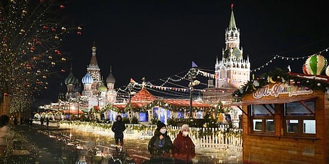 People walk past a Market set up in Red Square with the St. Basil's Cathedral, left, and the Spasskaya Tower, right, in Moscow, Russia, late Monday, Feb. 14, 2022.(Photo | AP)