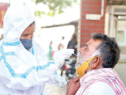 A health worker takes a swab sample from a passenger at Kempegowda Bus Station in Bengaluru on Wednesday
