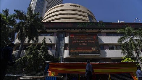 People watch the stock market index on a display screen on the facade of the Bombay Stock Exchange (BSE) building in Mumbai. 
