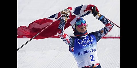 Norway's Therese Johaug celebrates after crossing the finish during the women's 30km mass start free cross-country skiing competition at the 2022 Winter Olympics