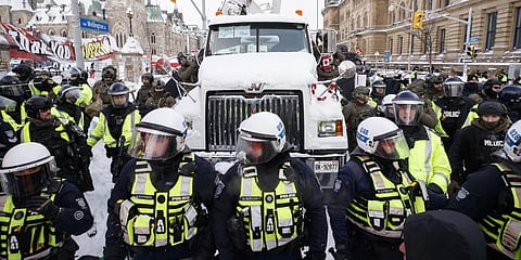 Police hang off a truck as authorities work to end a protest against COVID-19 measures in Ottawa, Saturday, Feb. 19, 2022.(Photo | AP)