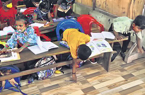 A student reaches for the pen that fell on the floor at St Joseph’s UP School in Thiruvananthapuram on Monday (Photo| EPS, B P Deepu)