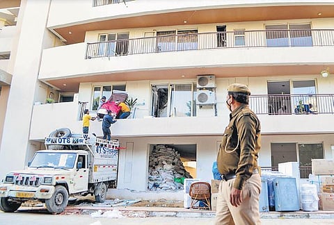 Workers shift household items of displaced residents of the Chintels Paradiso housing society in Gurugram on Tuesday, Feb 23, 2022. A portion of a building's roof collapsed on Feb 10. (Photo | PTI)