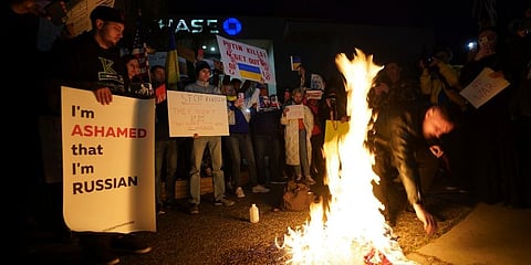 A Russian citizen burns a Russian flag as people protest the Russian invasion of Ukraine. (Photo | AP)