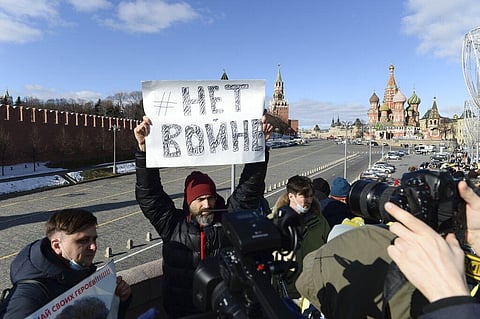 A man holds a poster which reads 'No War' as people lay flowers near the place where Russian opposition leader Boris Nemtsov was gunned down. (Photo | AP)