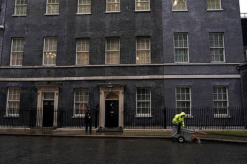 A worker sweeps in the rain and a police officer stands guard outside the door of 10 Downing Street, in London, Friday, Feb. 4, 2022. (Photo | AP)
