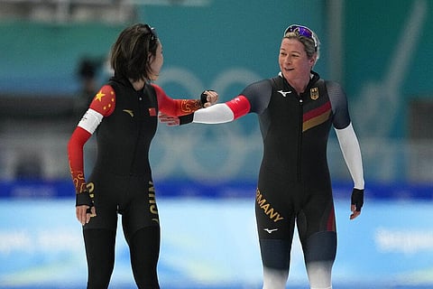 Ahenaer Adake of China, left, greets Claudia Pechstein of Germany, after Adake won their heat in the women's speedskating 3,000-meter race at the 2022 Winter Olympics. (Photo | AP)