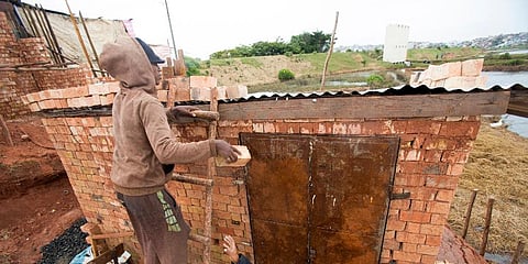 A man weighs down the roof of his home with bricks to stop it from flying away during bad weather in Antananarivo, Madagascar, Saturday, Feb. 5, 2022. (Photo | AP)