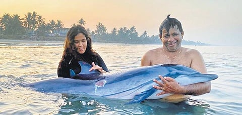 Diver Wilfred C Manuel and daughter Angel attending to the injured dolphin that beached at Moolamkuzhi in Kochi on Friday