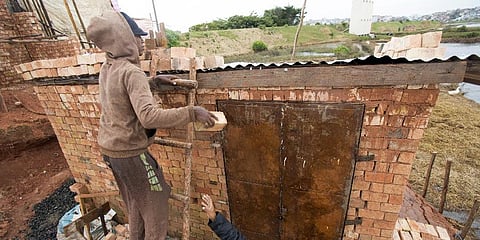 A man weighs down the roof of his home with bricks to stop it from flying away during bad weather in Antananarivo, Madagascar.(Photo | AP)