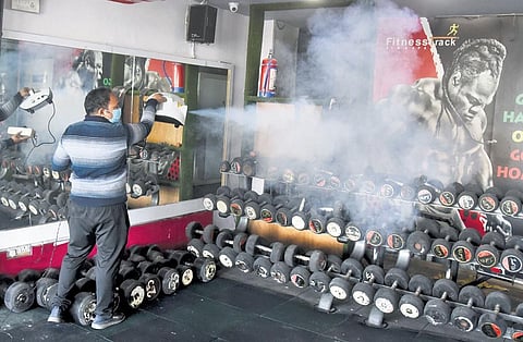 A worker sanitises equipment inside a gym in Delhi on Sunday. (Photo | Parveen Negi)