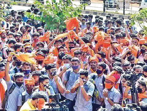 Two groups of students, wearing saffron stoles and turbans