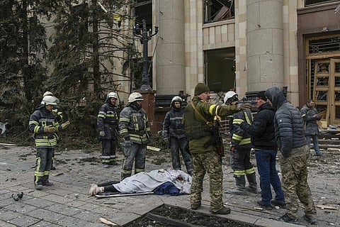 Ukrainian emergency service personnel and servicemen stand around a body of a victim following shelling of the City Hall building in Kharkiv, Ukraine. (Photo | AP)