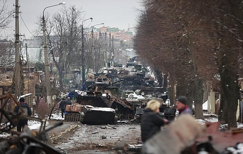 People look at the gutted remains of Russian military vehicles on a road in the town of Bucha, close to the capital Kyiv, Ukraine. (Photo | AP)