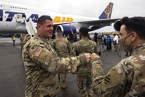 A line of soldiers with the U.S. Army's 87th Division Sustainment Support Battalion, 3rd Division Sustainment Brigade, right, get a fist bump from members of the command staff. (Photo | AP)