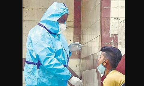 A medical staff collects swab samples from a man in Bengaluru