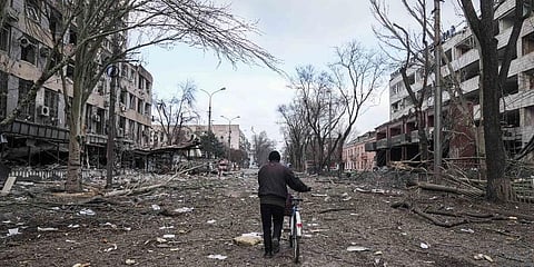 A man walks with a bicycle in a street damaged by shelling in Mariupol, Ukraine.
